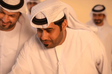 الاحتفال بالهوية الوطنية والموروث الثقافي الإماراتي، بورتريه مقرب لمجموعة من الرجال العرب الخليجيين الإماراتيين يرتدون الكندورة والغترة يؤدون رقصة العيالة بالعصي الخشبية، مشهد يعبر عن الفرح والتكاتف وروح الجماعة، مظهر من مظاهر الأصالة والعزة في المناسبات الوطنية والاجتماعية.