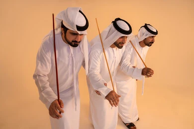 Preserving cultural heritage and authentic traditions, celebrating national and heritage occasions, performing Emirati folk arts, a portrait of a group of Emirati Gulf Arab men wearing the kandura and ghutrah performing the traditional Ayala dance, gestures of joy and pride in national identity, preserving cultural heritage and authentic traditions.