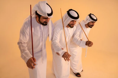 أداء الفنون الشعبية الإماراتية، الاحتفال بالمناسبات الوطنية والتراثية، بورترية لمجموعة من الرجال العرب الخليجيين الإماراتيين يرتدون الكندورة والغترة  يقومون بعرض رقصة العيالة التراثية، إيماءات السرور والفخر بالهوية الوطنية، الحفاظ على الموروث الثقافي والعادات الأصيلة