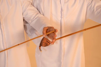 Expressions of pride and honor, celebrating national and heritage occasions, performing Emirati folk arts, a close portrait of a group of Emirati Gulf Arab men wearing the kandura and ghutrah performing the traditional Ayala dance, gestures of joy and pride in national identity, preserving cultural heritage and authentic traditions.