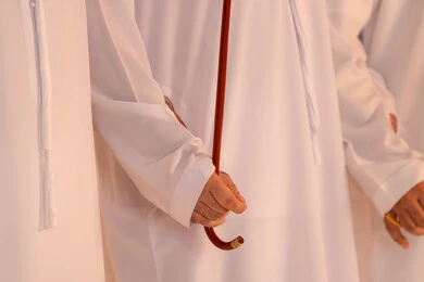The performance of Emirati folk arts, expressions of pride and honor, celebrating national and heritage occasions, a close portrait of a group of Emirati Gulf Arab men wearing kandura and ghutrah performing the traditional Ayala dance, gestures of joy and pride in national identity, preserving cultural heritage and authentic customs.