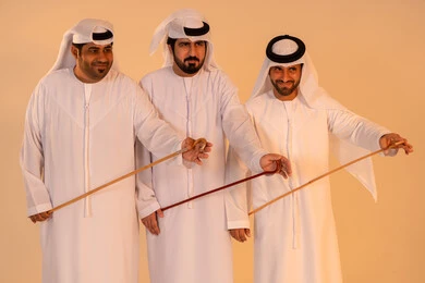 Gestures of joy and pride in national identity, preserving cultural heritage and authentic traditions, celebrating national and heritage occasions, performing Emirati folk arts, a portrait of a group of Arab Gulf Emirati men wearing the kandura and ghutrah performing the traditional Ayala dance.