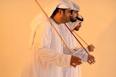 The performance of Emirati folk arts, celebrating national and heritage occasions, gestures of joy and pride in national identity, a portrait of a group of Emirati Gulf Arab men wearing the kandura and ghutrah performing the traditional Ayala dance, preserving cultural heritage and authentic customs.