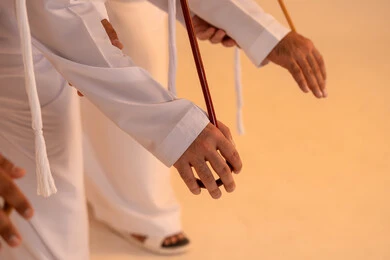 مظاهر الأصالة والعزة في المناسبات الوطنية، الاحتفال بالمناسبات الوطنية والتراثية، أداء الفنون الشعبية الإماراتية، بورترية مقرب ليد مجموعة من الرجال العرب الخليجيين الإماراتيين يرتدون الكندورة والغترة يقومون بعرض رقصة العيالة التراثية، إيماءات السرور والفخر بالهوية الوطنية، الحفاظ على الموروث الثقافي والعادات الأصيلة