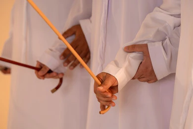 Expressions of pride and honor, celebrating national and heritage occasions, performing Emirati folk arts, a close portrait of a group of Emirati Gulf Arab men wearing the kandura and ghutrah performing the traditional Ayala dance, gestures of joy and pride in national identity, preserving cultural heritage and authentic traditions.
