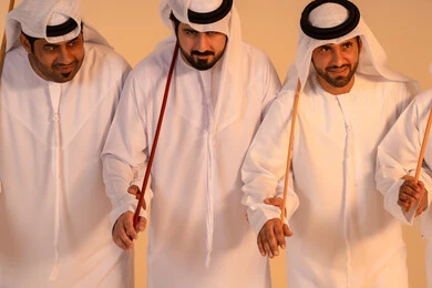 الاحتفال بالمناسبات الوطنية والتراثية، أداء الفنون الشعبية الإماراتية، بورترية لمجموعة من الرجال العرب الخليجيين الإماراتيين يرتدون الكندورة والغترة  يقومون بعرض رقصة العيالة التراثية، إيماءات السرور والفخر بالهوية الوطنية، الحفاظ على الموروث الثقافي والعادات الأصيلة