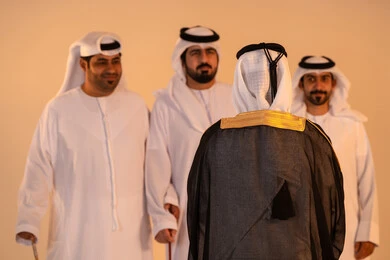 مظاهر الفرح والاحتفاء بالتراث الإماراتي الأصيل، بورتريه لمجموعة من الرجال العرب الخليجيين الإماراتيين يرتدون الكندورة والغترة يؤدون رقصة العيالة التقليدية بالعصي الخشبية، تجسيد للهوية الوطنية والانتماء، الحفاظ على العادات والتقاليد الشعبية في المناسبات الوطنية، أجواء احتفالية مفعمة بالفخر والاعتزاز.