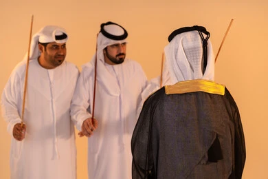 أداء الفنون الشعبية الإماراتية، الاحتفال بالمناسبات الوطنية والتراثية، بورترية لمجموعة من الرجال العرب الخليجيين الإماراتيين يرتدون الزي التقليدي يقومون بعرض رقصة العيالة التراثية، إيماءات السرور والفخر بالهوية الوطنية، الحفاظ على الموروث الثقافي والعادات الأصيلة