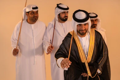 Gestures of joy and pride in national identity, celebrating national and heritage occasions, performing Emirati folk arts, a portrait of a group of Emirati Gulf Arab men wearing traditional attire performing the traditional Ayala dance, preserving cultural heritage and authentic customs.