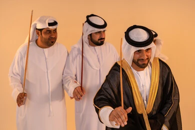 الاحتفال بالمناسبات الوطنية والتراثية، أداء الفنون الشعبية الإماراتية، بورترية لمجموعة من الرجال العرب الخليجيين الإماراتيين يرتدون الزي التقليدي يقومون بعرض رقصة العيالة التراثية، إيماءات السرور والفخر بالهوية الوطنية، الحفاظ على الموروث الثقافي والعادات الأصيلة
