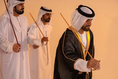 Performance of Emirati folk arts, celebrating national and heritage occasions, a portrait of a group of Emirati Gulf Arab men wearing traditional attire performing the traditional Ayala dance, gestures of joy and pride in national identity, preserving cultural heritage and authentic customs.