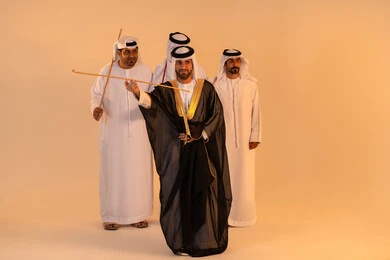 A portrait of a group of Emirati Gulf Arab men wearing the kandura and ghutrah performing the traditional Ayala dance with wooden sticks, embodying national identity and belonging, preserving popular customs and traditions during national occasions, manifestations of joy and celebration of the authentic Emirati heritage, a festive atmosphere filled with pride and honor.