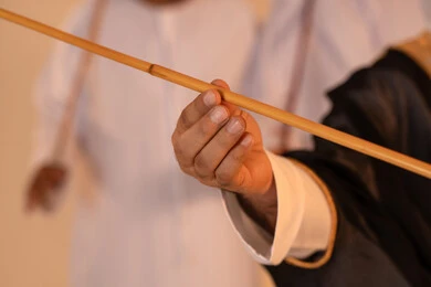 Celebrating national and heritage occasions, performing Emirati folk arts, a close portrait of a group of Arab Gulf Emirati men wearing traditional attire performing the heritage Ayala dance, gestures of joy and pride in national identity, preserving cultural heritage and authentic customs.