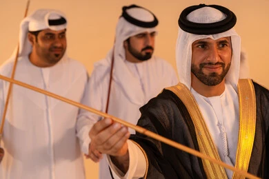Gestures of joy and pride in national identity, celebrating national and heritage occasions, performing Emirati folk arts, a portrait of a group of Emirati Gulf Arab men wearing traditional attire performing the traditional Ayala dance, preserving cultural heritage and authentic customs.