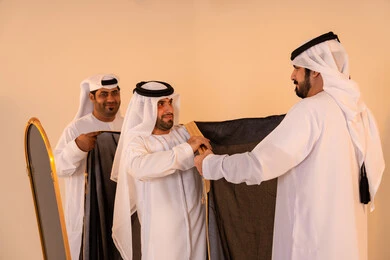 الاعتزاز بالهوية والتراث الإماراتي الأصيل ، بورتريه لرجل عربي خليجي إماراتي يرتدي البشت الأسود المطرز بالذهبي بمساعدة صديقين، الاستعداد للمناسبات الرسمية والاحتفالات الوطنية، مفهوم الأناقة والتراث والفخامه الاعتزاز بالهوية والتراث الإماراتي الأصيل ، بورتريه لرجل عربي خليجي إماراتي يرتدي البشت الأسود المطرز بالذهبي بمساعدة صديقين، الاستعداد للمناسبات الرسمية والاحتفالات الوطنية، مفهوم الأناقة والتراث والفخامه