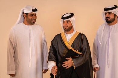 مفهوم الاناقة والاهتمام بالمظهر الخارجي ،الأخوة والتعاون في التحضير للمناسبات الرسمية، مظاهر الأصالة والفخامة، بورتريه لرجل عربي خليجي إماراتي يرتدي البشت الأسود المطرز بالذهبي بمساعدة صديقين، الاستعداد للاحتفالات الوطنية مفهوم الاناقة والاهتمام بالمظهر الخارجي ،الأخوة والتعاون في التحضير للمناسبات الرسمية، مظاهر الأصالة والفخامة، بورتريه لرجل عربي خليجي إماراتي يرتدي البشت الأسود المطرز بالذهبي بمساعدة صديقين، الاستعداد للاحتفالات الوطنية