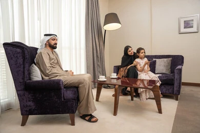 اجواء عائلية سعيدة، تعابير الفرح والسرور، برنامج كوميدي ترفيهي، قضاء وقت الفراغ بالتسلية والترفيه,عائلة عربيه خليجيه اماراتية ترتدي الزي التقليدي تجلس فى غرفه المعيشة يقومون بمشاهدة الفلم والمسلسل