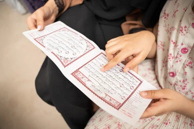 غرس المبادئ الإسلامية في نفوس الأولاد، الإجتهاد و الخشوع في العباده، تلاوة وقراءة كتاب الله تعالى، صورة مقربة ليد ام عربيه خليجيه سعودية تقوم بقراءة القراة الكريم برفقة ابنتها
