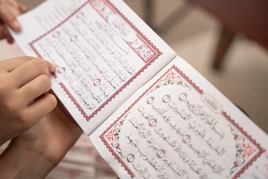 ترسيخ القيم الإسلامية لدى الأولاد، الإجتهاد و الخشوع في العباده، تلاوة وقراءة كتاب الله تعالى، صورة مقربة ليد ام عربيه خليجيه سعودية تقوم بقراءة القراة الكريم برفقة ابنتها