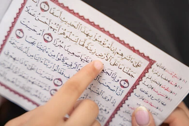 تعزيز الفطرة الاسلامية لدى الاولاد، الإجتهاد و الخشوع في العباده، تلاوة وقراءة كتاب الله تعالى، صورة مقربة ليد ام عربيه خليجيه سعودية تقوم بقراءة القراة الكريم برفقة ابنتها