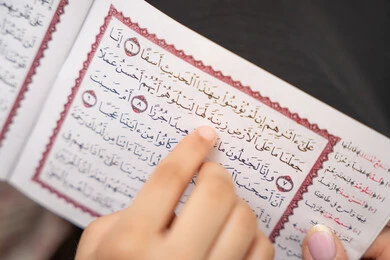 الإجتهاد و الخشوع في العباده، تلاوة وقراءة كتاب الله تعالى، صورة مقربة ليد ام عربيه خليجيه سعودية تقوم بقراءة القراة الكريم برفقة ابنتها، تعزيز الفطرة الاسلامية لدى الاولاد