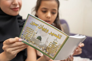 العبادة والتقرب الى الله، تعليم الاولاد على التثقيف والمطالعة، مفهوم السعاده الأسرية وإهتمام الأم بالأبناء، سيده سعودية تقوم بقضاء وقت ممتع مع الأبناء، صورة مقربة لام عربية خليجيه اماراتية ترتدي العباءة السوداء تقوم بقراءة تفسير و بيان السور برفقة ابنتها