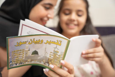 مفهوم السعاده الأسرية وإهتمام الأم بالأبناء، تعليم الاولاد على التثقيف والمطالعة، سيده سعودية تقوم بقضاء وقت ممتع مع الأبناء، صورة مقربة لام عربية خليجيه اماراتية ترتدي العباءة السوداء تقوم بقراءة تفسير و بيان السور برفقة ابنتها، العبادة والتقرب الى الله