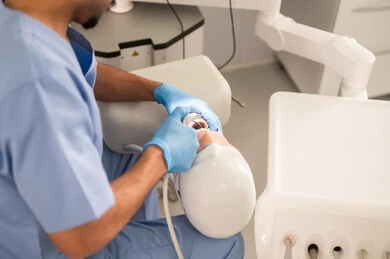 معالجة التلف السني الناتج عن النخر، صورة مقربة ليد طالب جامعي بكلية الأسنان يرتدي القفازات يقوم بفحص مجسم به طاقم أسنان، مفهوم التدريب العملي، المعدات والادوات اللازمة لإجراء الفحوصات, الأساليب العلاجية المتبعة للعناية بالفم