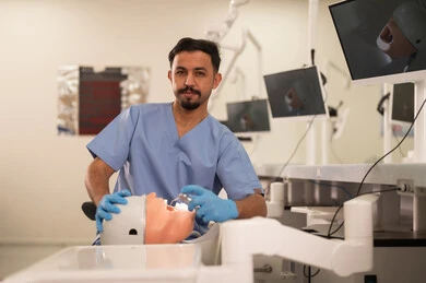 علاج نخر الأسنان بشكل علاجي، طالب جامعي بكلية الأسنان يرتدي القفازات يقوم بفحص مجسم به طاقم أسنان، مفهوم التدريب العملي، المعدات والادوات اللازمة لإجراء الفحوصات, الأساليب العلاجية المتبعة للعناية بالفم