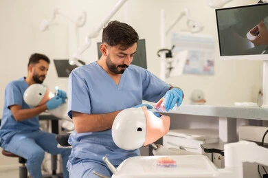 التعامل مع مستلزمات ومواد طب الأسنان، طرق علاجية للعناية بالأسنان، معالجة التسوس وتركيب الحشوات، مجموعة من الطلاب الجامعيين بكلية الأسنان يرتدون القفازات يقومون بفحص الأسنان على مجسم