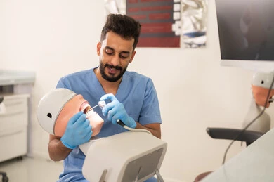 Cavity treatment and filling placement, a university student in dental school wearing gloves examining a model with a dental set, the concept of practical training, the equipment and tools necessary for conducting examinations, the therapeutic methods used for oral care.