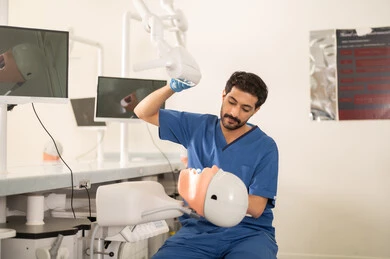 Removal of cavities and restoration of teeth, a university student in the dental college wearing gloves examining a model with a set of teeth, the concept of practical training, the equipment and tools necessary for conducting examinations, the therapeutic methods used for oral care.
