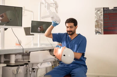 معالجة التسوس السني، طالب جامعي بكلية الأسنان يرتدي القفازات يقوم بفحص مجسم به طاقم أسنان، مفهوم التدريب العملي، المعدات والادوات اللازمة لإجراء الفحوصات, الأساليب العلاجية المتبعة للعناية بالفم