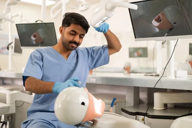 Treatment of dental cavities, a university student in the dental college wearing gloves examining a model with a set of teeth, the concept of practical training, the equipment and tools necessary for conducting examinations, the therapeutic methods used for oral care.