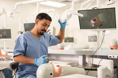 Removal of dental caries, a university student in the dental school wearing gloves examining a model with a set of teeth, the concept of practical training, the equipment and tools necessary for conducting examinations, the therapeutic methods used for oral care.