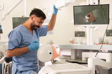 Treatment of tooth decay, a university student in the dental college wearing gloves examining a model with a set of teeth, the concept of practical training, the equipment and tools necessary for conducting examinations, the therapeutic methods used for oral care.