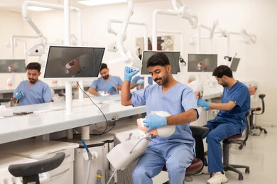 Operating medical equipment for examination and treatment, therapeutic methods for dental care, treating cavities and placing fillings, a group of university students in the dental college wearing gloves examining teeth on a model.