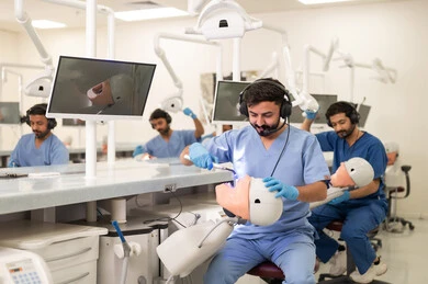 توظيف أدوات ومواد طب الأسنان، طرق علاجية للعناية بالأسنان، معالجة التسوس وتركيب الحشوات، مجموعة من الطلاب الجامعيين بكلية الأسنان يرتدون القفازات يقومون بفحص الأسنان على مجسم