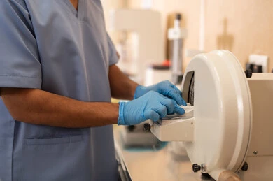 إصلاح الأسنان المتضررة بالتسوس بالحشوات المناسبة، مفهوم التدريب العملي، صورة مقربة ليد طالب جامعي بكلية الأسنان يرتدي القفازات يقوم باستخدام الاجهزة الطبية