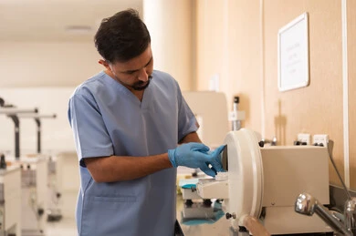 معالجة التلف الناتج عن التسوس ووضع الحشوات، مفهوم التدريب العملي، طالب جامعي بكلية الأسنان يرتدي القفازات يقوم باستخدام الاجهزة الطبية