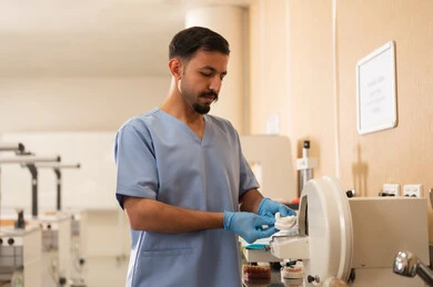 إزالة التسوس وتركيب الحشوات السنية، مفهوم التدريب العملي، معالجة التسوس وتركيب الحشوات، طالب جامعي بكلية الأسنان يرتدي القفازات يقوم باستخدام الاجهزة الطبية