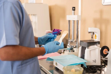 استخدام الأدوات الطبية الخاصة بطب الأسنان، مفهوم التدريب العملي، الأساليب العلاجية المتبعة للعناية بالفم، معالجة التسوس وتركيب الحشوات، صورة مقربة لطالب جامعي بكلية الأسنان يرتدي القفازات يقوم تحضير المواد الطبية لحشوات الأسنان