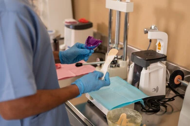 تشغيل معدات وأدوات فحص الأسنان، مفهوم التدريب العملي، الأساليب العلاجية المتبعة للعناية بالفم، معالجة التسوس وتركيب الحشوات، صورة مقربة لطالب جامعي بكلية الأسنان يرتدي القفازات يقوم تحضير المواد الطبية لحشوات الأسنان