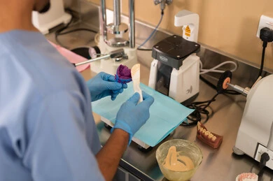 Dealing with dental clinic tools, the concept of practical training, therapeutic methods used for oral care, treating cavities and placing fillings, a close-up image of a university student in the dental college wearing gloves preparing medical materials for dental fillings.
