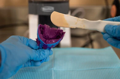 توظيف معدات وأدوات العلاج السني، مفهوم التدريب العملي، الأساليب العلاجية المتبعة للعناية بالفم، معالجة التسوس وتركيب الحشوات، صورة مقربة ليد طالب جامعي بكلية الأسنان يرتدي القفازات يقوم تحضير المواد الطبية لحشوات الأسنان