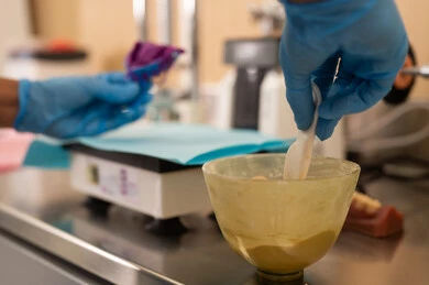 The use of dental devices in medical work, the concept of practical training, the therapeutic methods used for oral care, the treatment of cavities and the placement of fillings, a close-up image of a university dental student wearing gloves preparing medical materials for dental fillings.