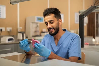 إعداد الحشوات الخاصة بإصلاح الأسنان، معالجة الأسنان من التسوس، الأساليب العلاجية المتبعة للعناية بالفم، التعليم الجامعي فى المملكه العربيه السعوديه ، المعدات والادوات اللازمة لإجراء الفحوصات، طالب عربي جامعي سعودي بكلية الأسنان يرتدي القفازات يقوم بنحت طاقم أسنان