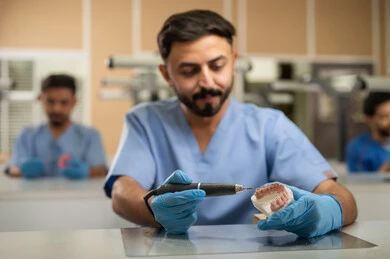 علاج الأسنان المتضررة بالتسوس وتركيب الحشوات العلاجية، مجموعة من الطلاب الجامعيين بكلية الأسنان يرتدون القفازات يقومون بفحص مجسم طاقم أسنان، استخدام معدات وأدوات طب الأسنان، الأساليب العلاجية المتبعة للعناية بالفم