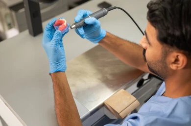 علاج التسوس ونخر الأسنان، مفهوم التدريب العملي، المعدات والادوات اللازمة لإجراء الفحوصات، صورة مقربة لطالب عربي خليجي سعودي بكلية الأسنان يرتديان القفازات يقوم بفحص طاقم أسنان، الأساليب العلاجية المتبعة للعناية بالفم