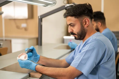 The concept of practical training, treatment of decay and cavities, the equipment and tools necessary for conducting examinations, a close-up side image of two Arab Gulf Saudi students in the dental college wearing gloves examining a dental set, the therapeutic methods used for oral care.